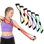 A person exercises with a red resistance band, pulling it with both hands. Five other resistance bands in different colors (yellow, red, purple, blue, green) are displayed beside them. The person is wearing a purple sports top and black leggings.