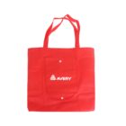 A red tote bag with two handles and a small pocket on the front. The pocket has the word AVERY and a triangular logo printed in white.