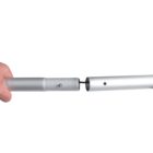 A hand is holding two silver metal tubes being connected together. One tube has a small metal button that fits into a hole in the other tube, allowing them to lock in place. The background is plain white.