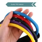 Hand holding five colorful resistance bands in blue, red, black, purple, and yellow. A label above reads Quality TPE material indicating the bands are made from thermoplastic elastomer.