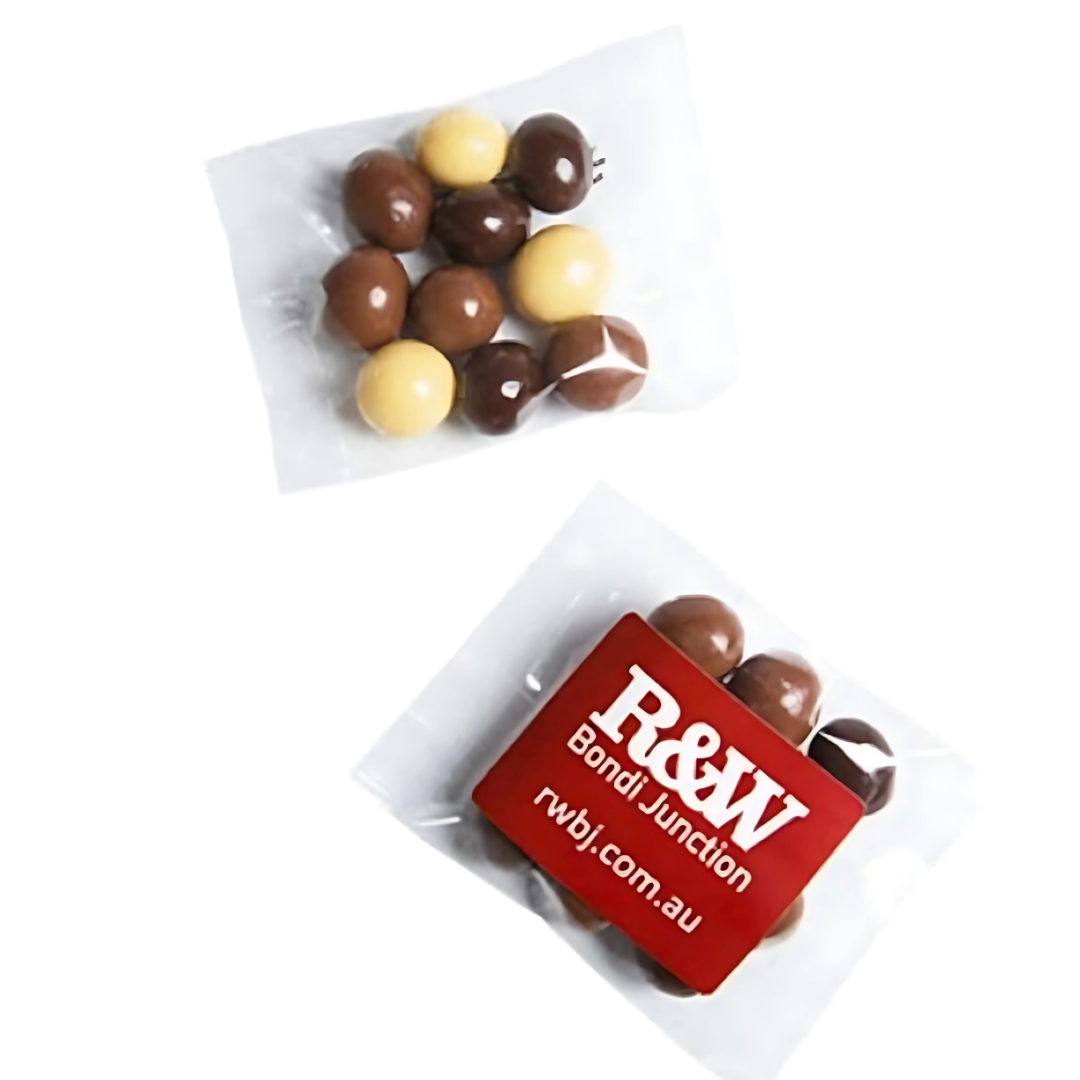Two small clear bags hold 25g of mixed brown and beige chocolate-covered candies, resembling delightful coffee beans. One bag features a red label with white text R&W Bondi Junction rwjbj.com.au, showcasing meticulous printing.