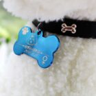 Close-up of a fluffy pet wearing a black collar with a silver bone charm. A blue, bone-shaped tag featuring a paw print, engraved design, and a symbol is attached to the collar.