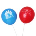 A blue balloon with the Huawei logo and text, and a red balloon with a white illustration of a smiling dog wearing a scarf, both attached to sticks.