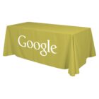 A rectangular table covered with a yellow tablecloth featuring the word Google in large white letters. The table is set against a plain white background.