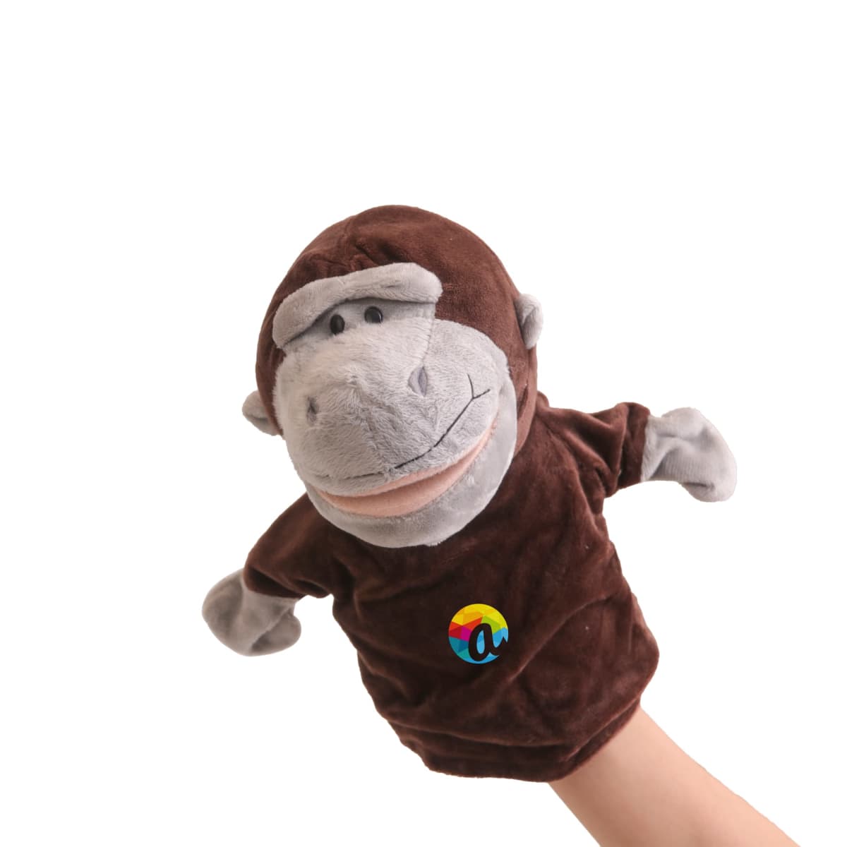 A brown and gray monkey hand puppet with a colorful logo on its chest, worn on a persons hand, against a plain white background.