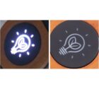 Two circular icons depicting a light bulb with a leaf inside. The left icon is illuminated, glowing white on a dark background. The right icon is unlit, with a white outline on a dark surface, surrounded by a wooden border.