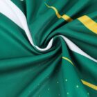 Close-up of green fabric with yellow and white stripes, twisted into a spiral. The fabric has a smooth texture and subtle decorative patterns, with small yellow dots visible on the surface.