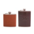 Two hip flasks, one wrapped in brown leather with MS Company embossed, and the other in dark brown leather with an M logo in a square design. Both have metallic caps and are standing upright.