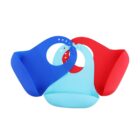 Three silicone bibs in blue, teal, and red are arranged overlapping each other. Each bib features adjustable neck closures and a wide pocket at the bottom. The smooth texture and bright colors are prominent.