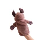 A hand holds up a plush brown puppet against a white background. The puppet has pointy ears and arm-like appendages, giving it an animal-like appearance.