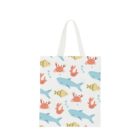 A white tote bag with handles featuring a playful pattern of blue sharks, orange crabs, pink shrimp, and light green fish, accompanied by blue bubbles. The design is set against a plain white background.