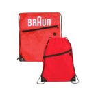 Red drawstring backpacks with black strings. One backpack displays the word BRAUN in white letters. Both bags have black zipper pockets and metal grommets at the corners.