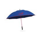 Blue umbrella with a red trim and handle, featuring a red logo with text. The handle is straight and black, contrasting with the umbrellas vibrant colors. The umbrella is open and isolated against a white background.