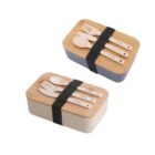Two rectangular bento lunch boxes with wooden lids secured by black elastic bands. Each lid has a set of wooden cutlery: a fork, spoon, and knife. One box is beige, and the other is gray.