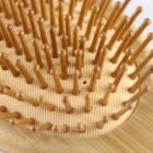 Close-up of a wooden hairbrush with long, rounded bristles. The bristles are attached to a light-colored base, providing a natural and organic appearance. The focus is on the texture and pattern of the bristles.