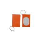 Two orange rectangular keychains are shown. One is closed, and the other is open, revealing a mirror inside. Both have metal rings attached.