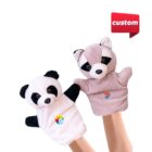 Two hand puppets: a panda wearing a white outfit with a rainbow logo and a raccoon in a pink outfit with a colorful circular logo. Both are raised by hands against a white background with a custom sign in the top right corner.