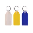 Three rectangular key tags with metal rings, arranged side by side. The tags are white, yellow, and blue from left to right, each with a blank label space.