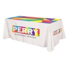 A white table with a colorful custom tablecloth displaying the words Perry Business Center in bold, multicolored letters. The top of the tablecloth features a geometric pattern with various bright colors.