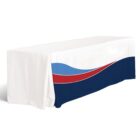 A long table covered with a white tablecloth featuring a design of a blue, red, and dark blue wave pattern along the side.