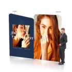 A display features two panels with images of a woman showcasing jewelry. The left panel shows her in profile adjusting earrings. The right panel has her smiling, touching her face. A man in a suit stands beside the display. Text reads Jewelry Photography.