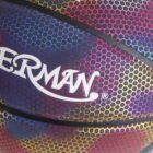 Close-up of a colorful basketball with a hexagonal pattern in shades of purple, red, yellow, and blue. The word SPERMAN is printed in white letters across the surface.
