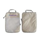 Two beige travel packing cubes with gray zippers and handles. One has a mesh front pocket with a purple INTERLINKAGE logo, and the other is plain. Theyre standing upright, showing both the front and back sides.