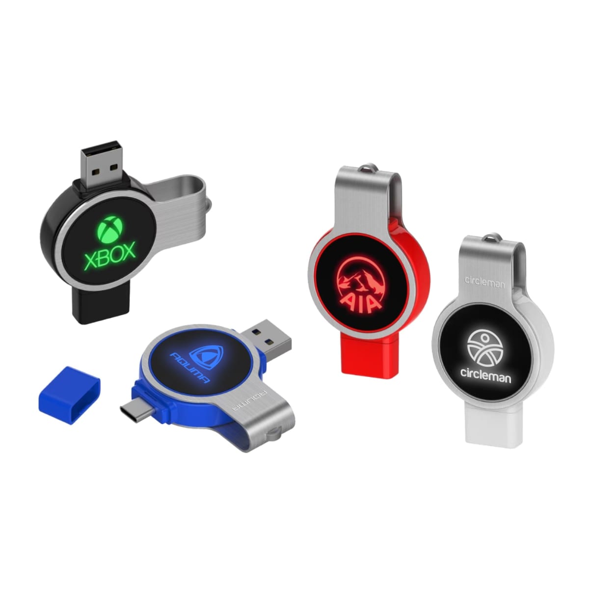 Four swivel USB flash drives with logos: Xbox in green, AIA in red, Polman in blue, and Circleman in white. Each has a sleek design with USB connectors exposed and a blue cap nearby.