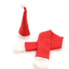 A small Santa hat with a white trim and pom-pom next to a matching red and white scarf on a plain white background.