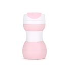 A pink and white plastic sippy cup with a wide base, contoured middle, and a closed spout lid. The cup has a modern design and is set against a plain white background.