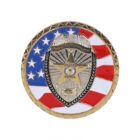 A round police badge with a gold and silver design features a shield in the center. Behind the shield, a flag pattern with stars and stripes is visible. The words Duty, Honor, Integrity are inscribed at the top.
