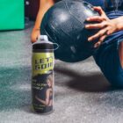 A water bottle labeled LETS GO!!! near a person holding a black exercise ball.