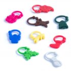 Nine colorful rubber keychains shaped like holiday-themed items: pink gift, red Santa, brown gingerbread man, green tree, blue angel, yellow star, red stocking, green holly, and white snowman, arranged on a white background.