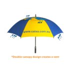 A blue and yellow umbrella with the website www.caixa.com.au printed on it. It features a double-canopy design with arrows indicating airflow. The text below reads: *Double-canopy design creates a vent.