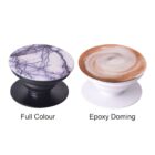 Two round phone grips are shown. The left one has a full-color design with a purple marbled pattern on a black base. The right one has an epoxy doming with a swirl pattern on a white base. Labels indicate Full Colour and Epoxy Doming.