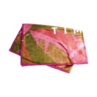 A soft blanket featuring abstract pink, gold, and green patterns with a pink border. The design includes large, overlapping shapes and partial lettering, creating a modern and artistic look.