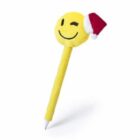 A pen with a plush cover featuring a yellow, winking smiley face wearing a red and white Santa hat.