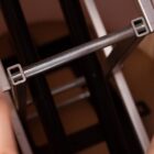 Close-up view of metal bars forming a geometric structure with a rectangular design. The image shows intersecting metal rods and frames in silver and dark colors, creating a modern, industrial appearance.