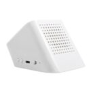 A white, triangular-shaped tabletop speaker with a perforated front panel. It has a USB charging port and control buttons on the side. The speaker rests on a flat surface, angled slightly upward.