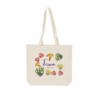 A cream-colored tote bag with long handles features the word Love in blue and life is good in red beneath it. Colorful leaves in pink, green, yellow, and orange surround the text.