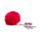 A fluffy, red pom-pom keychain attached to three keys and a red circular tag on a white background.