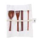 A set of wooden utensils including a spoon, fork, chopsticks, and a stirring stick are neatly placed inside a white fabric pouch with a snap closure. The utensils are secured with an elastic band.