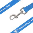 Close-up of a blue lanyard with a metal clip. The lanyard features the white text Transforming Lives™ and a logo with triangular shapes on a square background. The design repeats along the fabric.