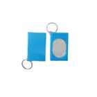 Two blue keychains with metal rings. One is closed, while the other is open, revealing an oval-shaped clear window for inserting a label or photo.