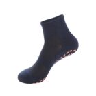 A single dark blue ankle sock with textured patterns and pink grip dots on the sole, viewed from the side against a white background.