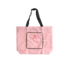A pink tote bag with black handles, featuring a front pocket outlined in black. The pocket has a zipper and displays a red logo and text. The bag is set against a white background.