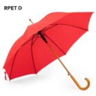 A red umbrella with a wooden handle is open against a plain white background. The handle is curved, and the fabric is smooth. The letters RPET with a recycling symbol are in the top left corner.