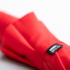Close-up of a red fabric with a REPL label attached. The fabric is folded, showcasing its texture and vibrant color. The label features a minimal design, indicating possible brand or product information.