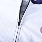 Close-up of a white zippered garment with a subtle texture. The partially opened zipper reveals a gray inner lining. A colorful circular logo is visible on the fabric near the zipper.
