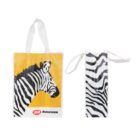Two tote bags featuring zebra designs. The left bag shows a zebra head on a yellow background with IGR Runcorn text. The right bag displays black and white zebra stripes. Both have white handles.